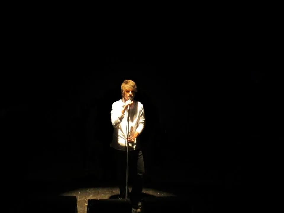 Gabriele Sarti singing under a spotlight in a dark room